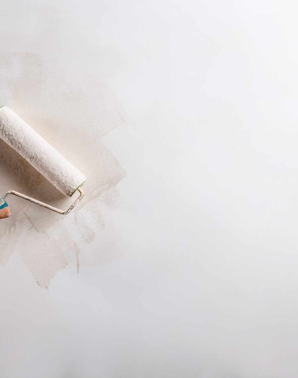 Close up photo of hand painting wall with roller in white color. Copy space.