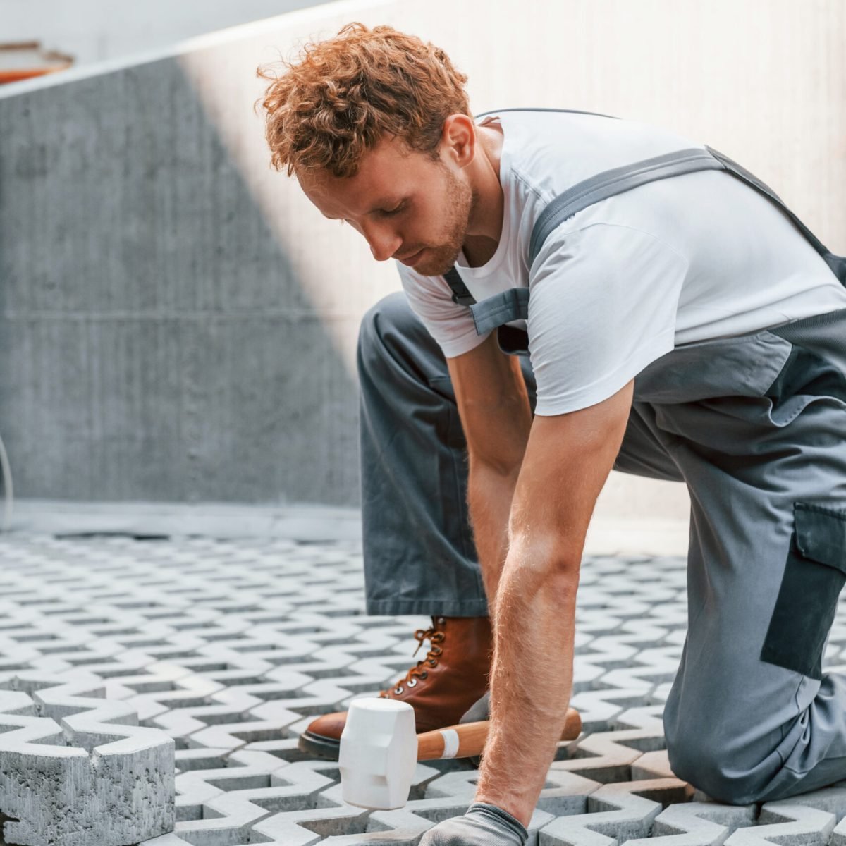 Sitting outdoors. Young man working in uniform at construction at daytime.